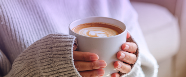 Mãos de um casal segurando uma xícara de café